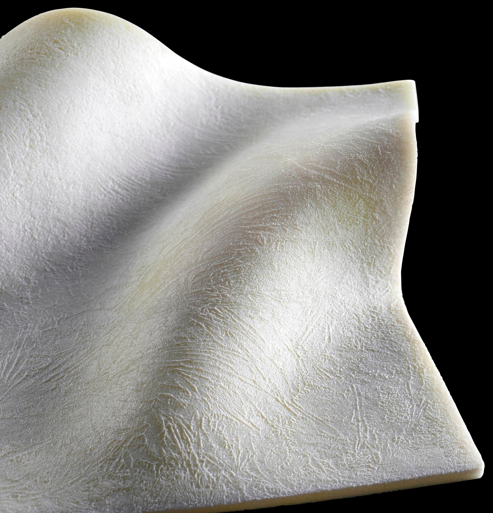 medical product photography of white medical solid mesh product in a wave form on black background