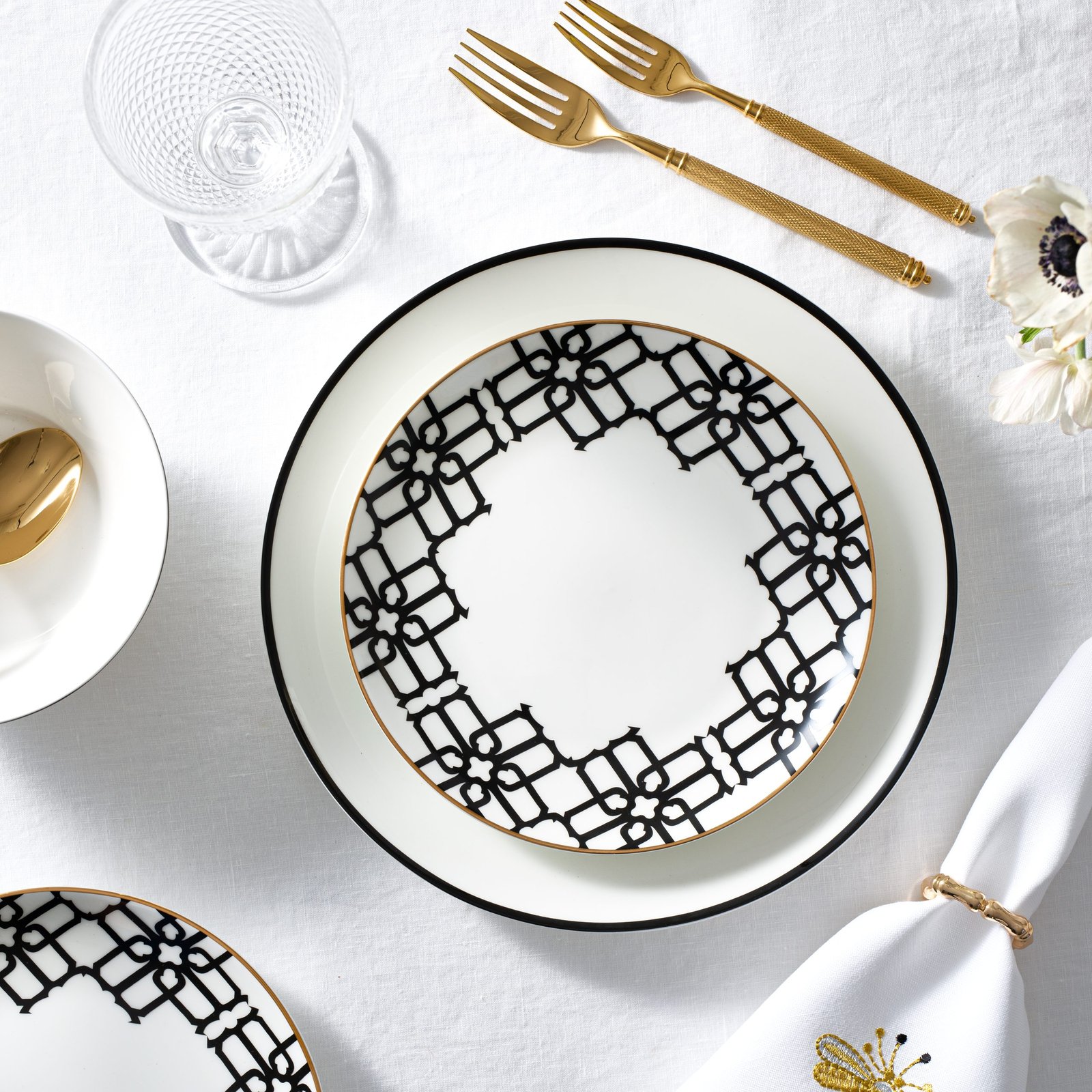 product lifestyle photography of white and black patterned dinnerware set with gold silverware set