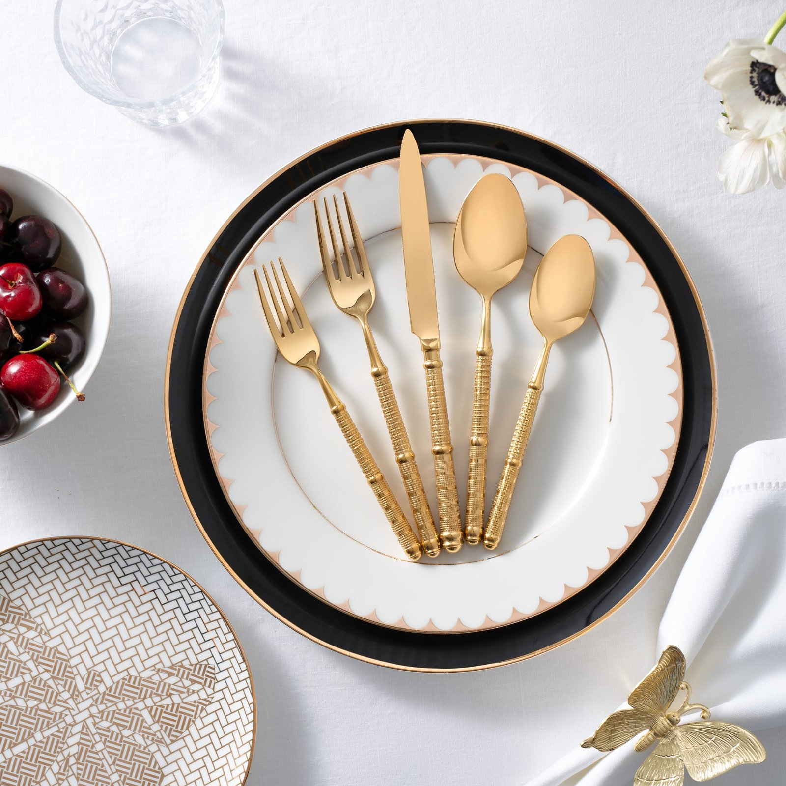 product lifestyle photography of white black and gold dinnerware set with gold silverware set on dinner plate