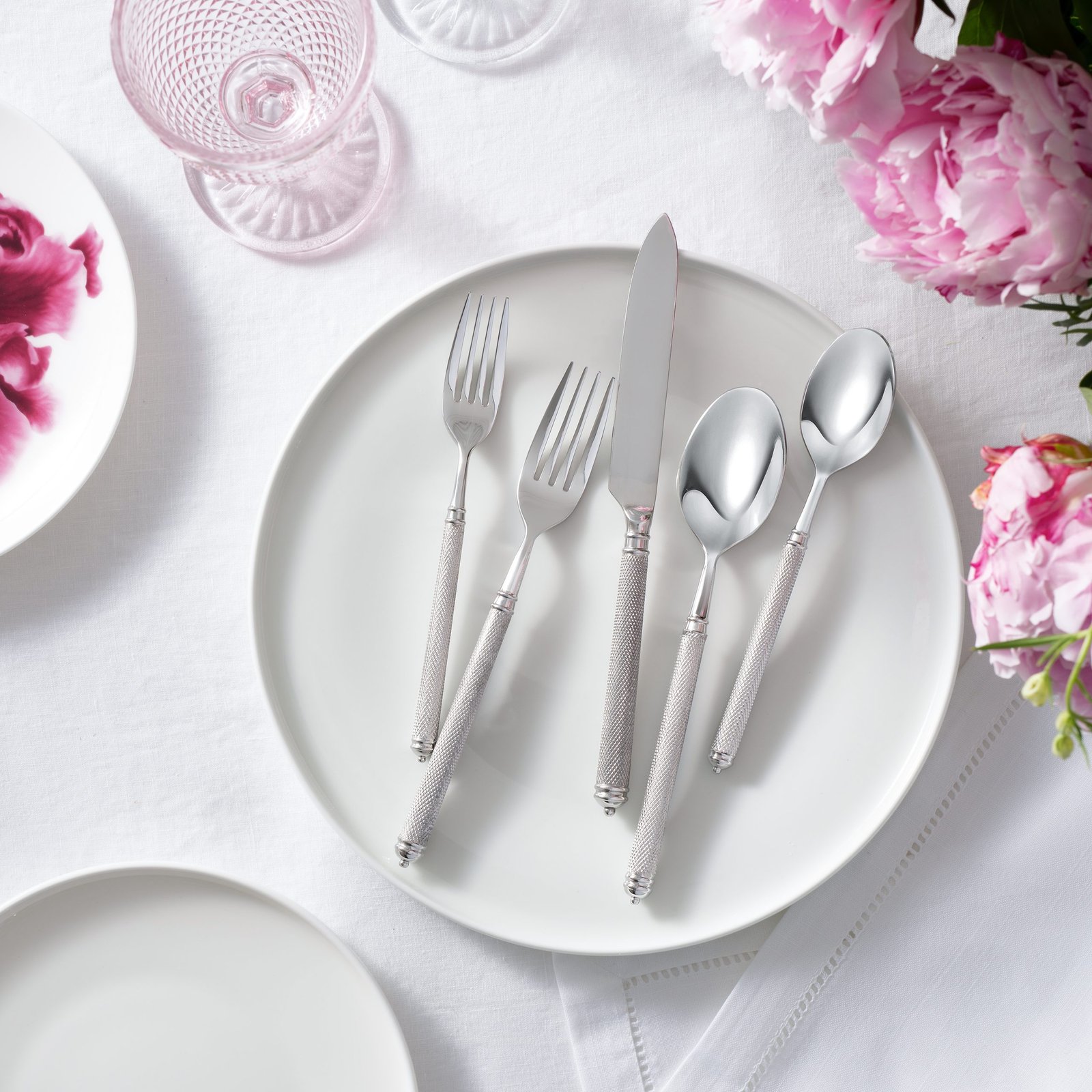 product lifestyle photography of white dinnerware set with silver silverware set on dinner plate