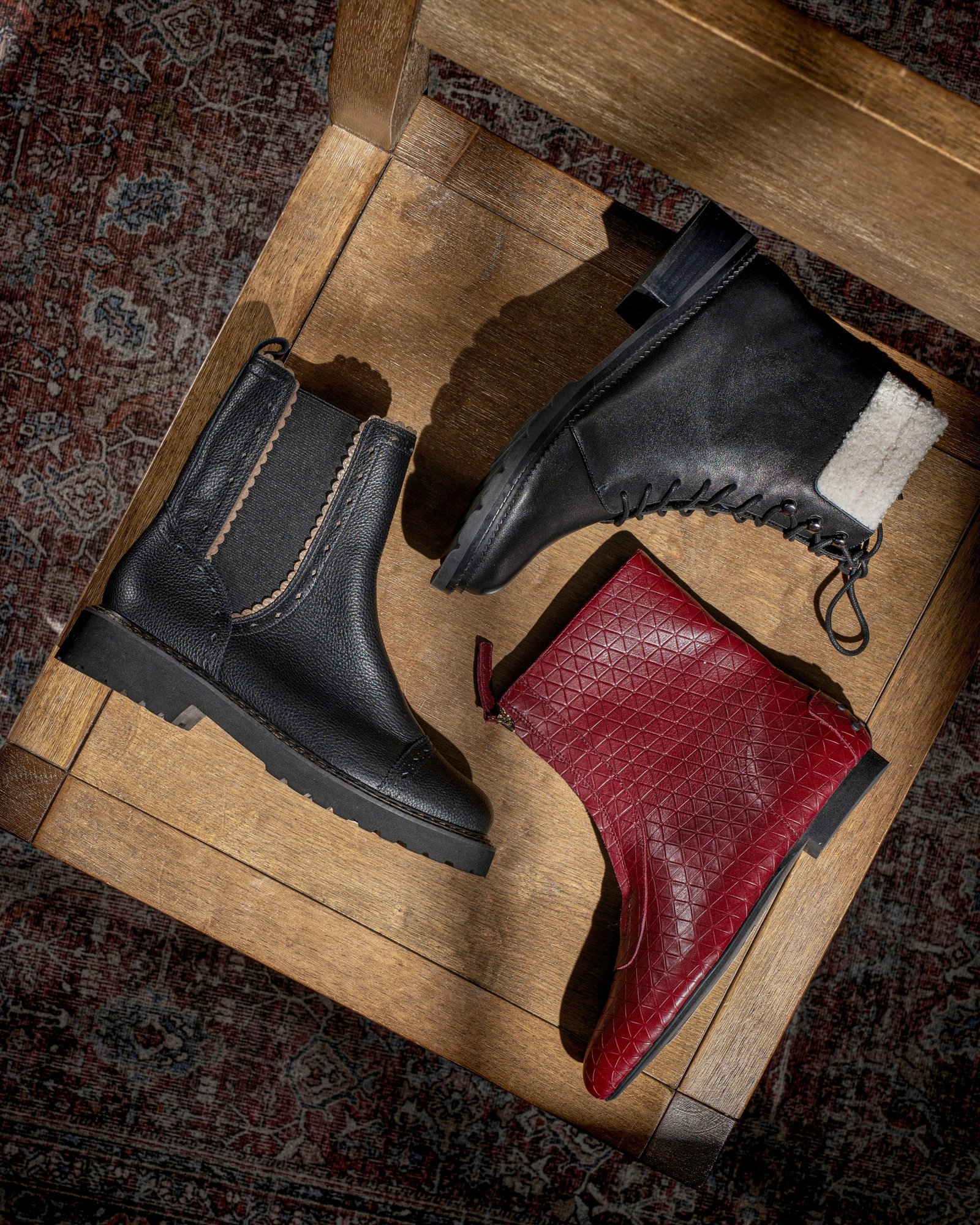 product lifestyle photography of red and black women's boots on tan wooden chair with shadows