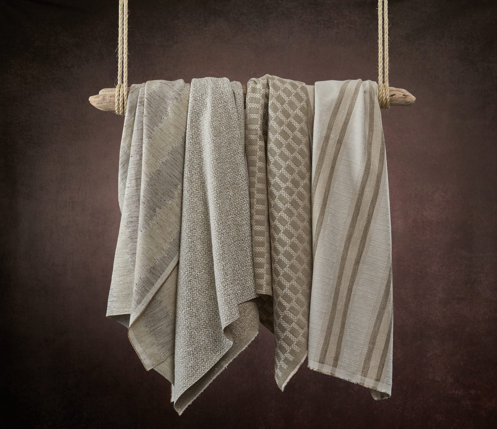 product lifestyle photography of earth colored fabrics hanging from drift wood swing