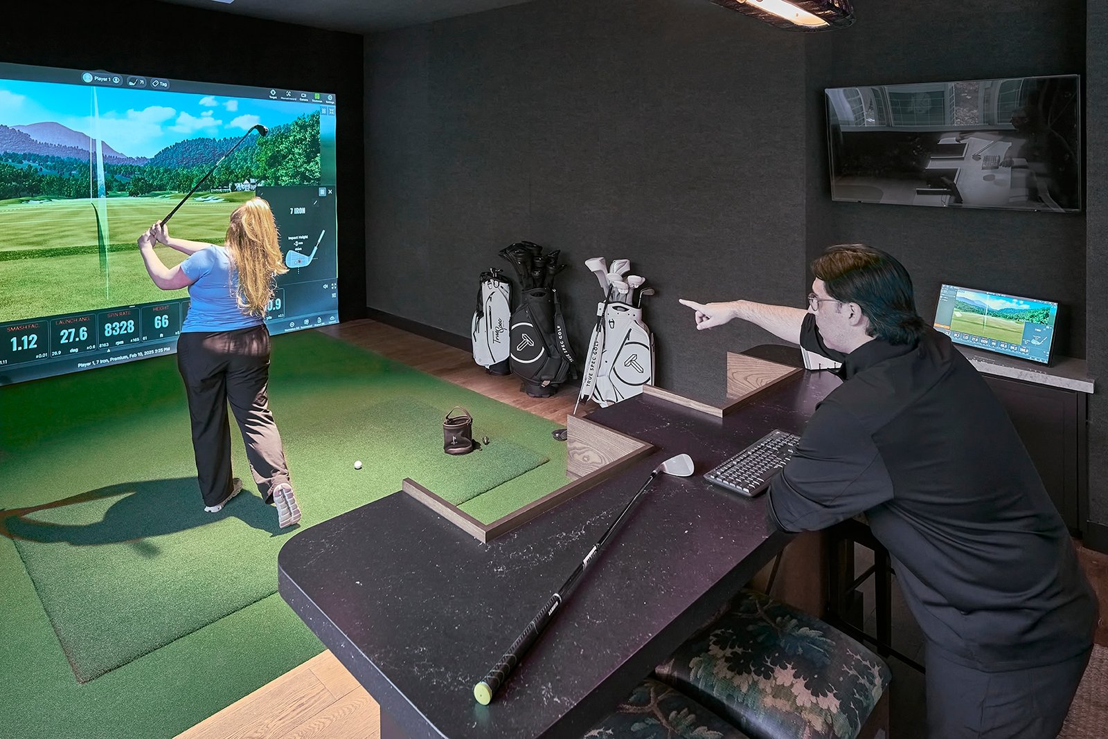 product lifestyle photography of true spec golf, indoor golf simulation with female student and male instructor