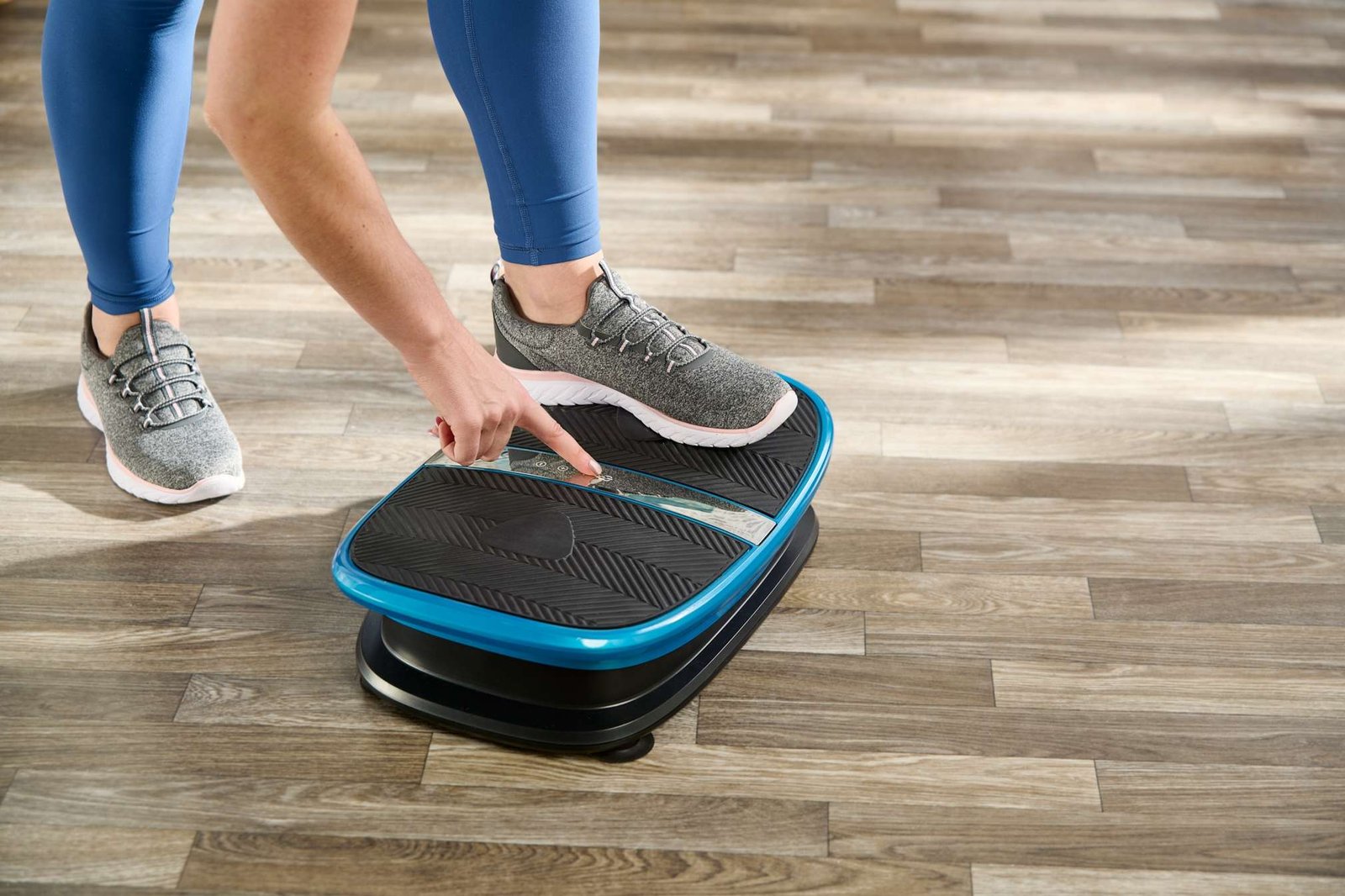 product lifestyle photography of female model in living room set. finger pushing button on exercise machine product